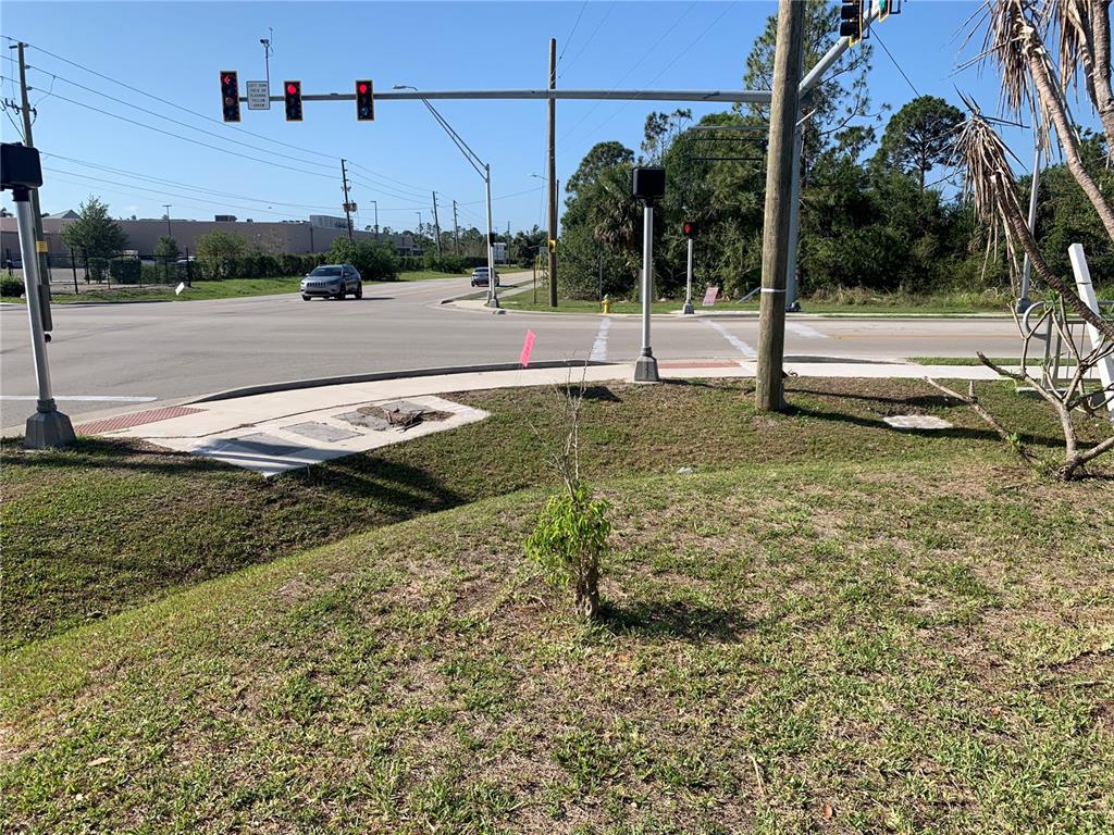 A view of a street intersection with traffic lights, a sidewalk, and a small tree — 23540 PEACHLAND BOULEVARD, PORT CHARLOTTE, FL