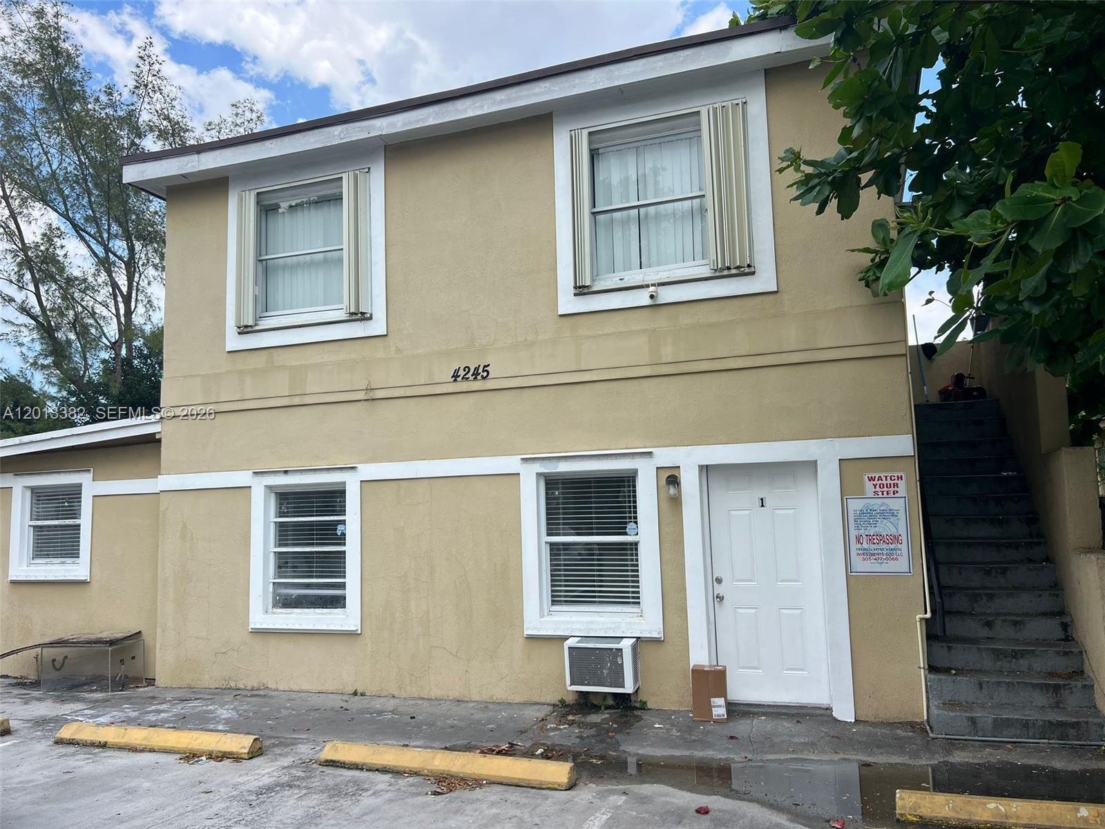 A two-story tan building with a white door, exterior stairs, and a parking lot — 4245 NW 24th Ave, Miami FL 33142, MIAMI, FL