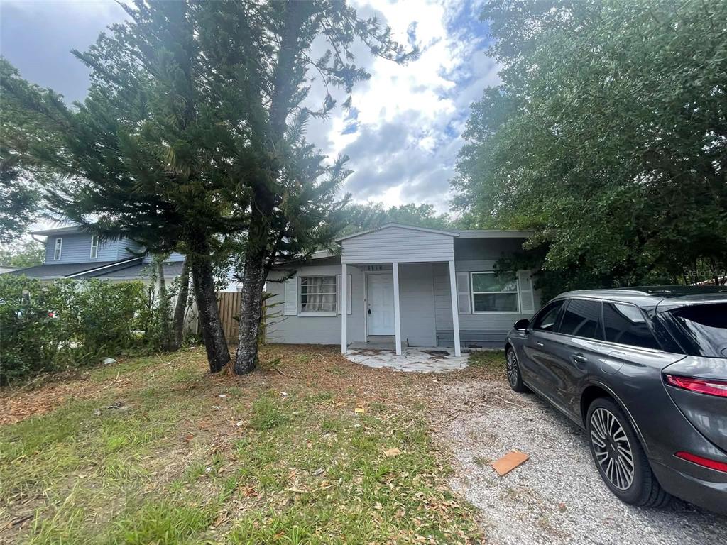 A single-story gray house with a covered entryway and a gravel driveway — 8716 N TANGERINE PLACE, TAMPA, FL