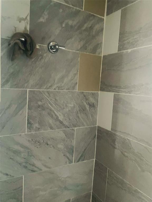 A shower wall featuring gray marble-look tiles and a single chrome shower handle — 8716 N TANGERINE PLACE, TAMPA, FL