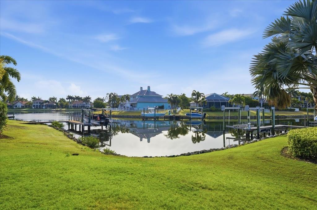A view of a canal with boat docks and houses under a blue sky — 5303 FISHERSOUND LANE, APOLLO BEACH, FL