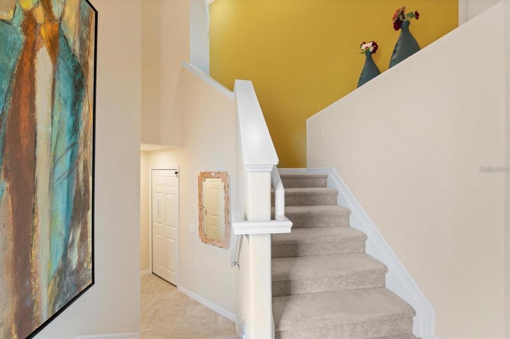 A carpeted staircase with a white railing leads upward next to a yellow wall — 416 WINDING BROOK LANE UNIT 102, BRADENTON, FL
