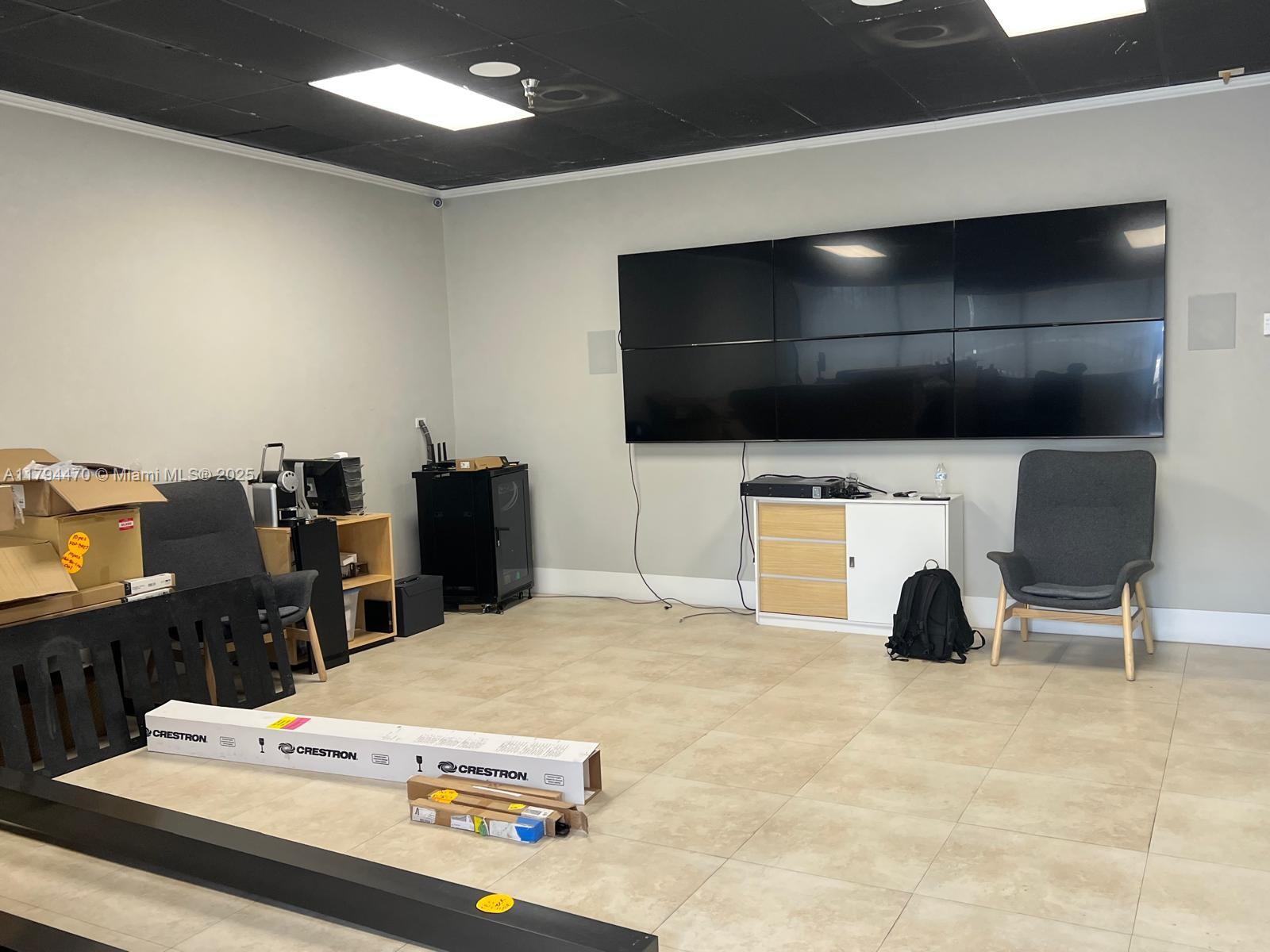 A room with a large wall-mounted video display, tile flooring, and scattered office equipment — 2330 NW 102nd Pl, Doral FL 33172, DORAL, FL
