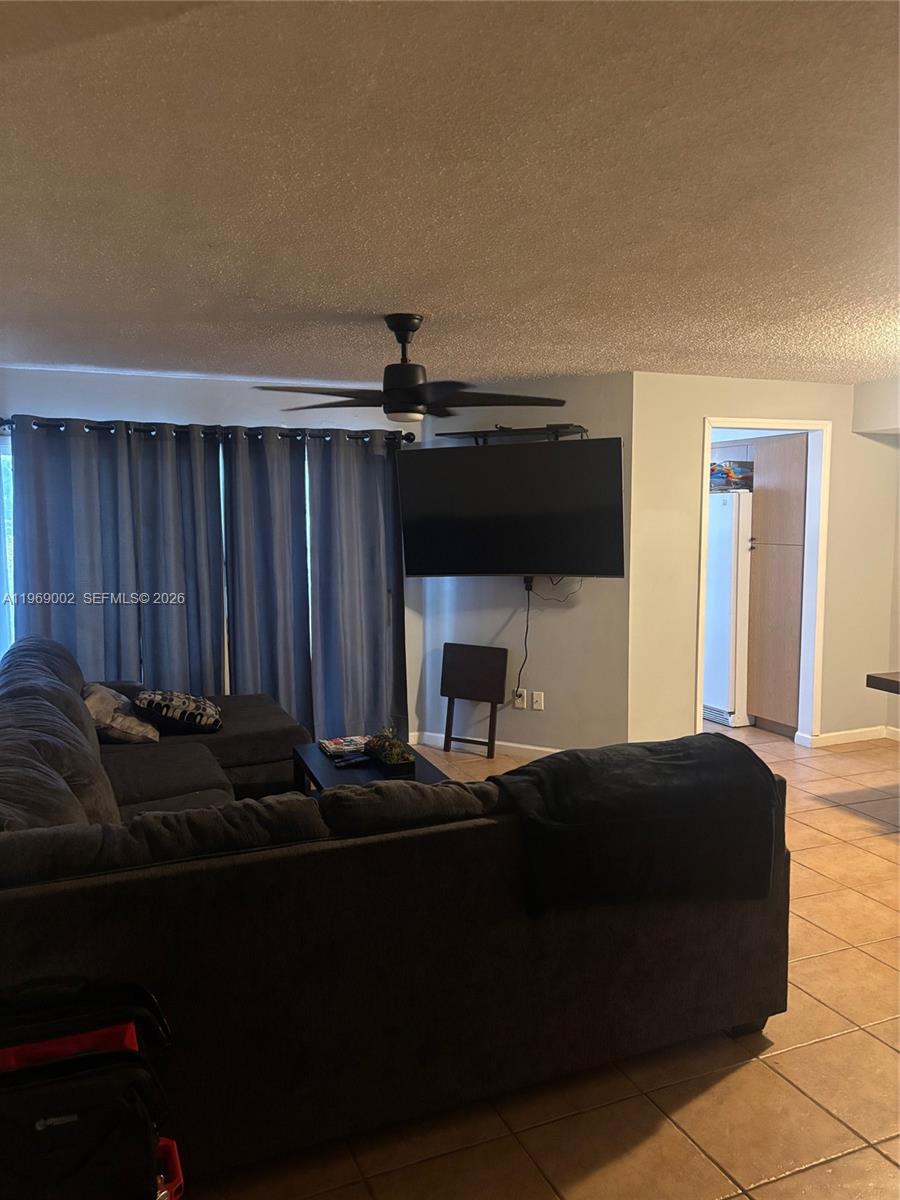 A living room features a sectional sofa, a wall-mounted television, and tile flooring — 2249 SE 27th Dr # D, Homestead FL 33035, HOMESTEAD, FL