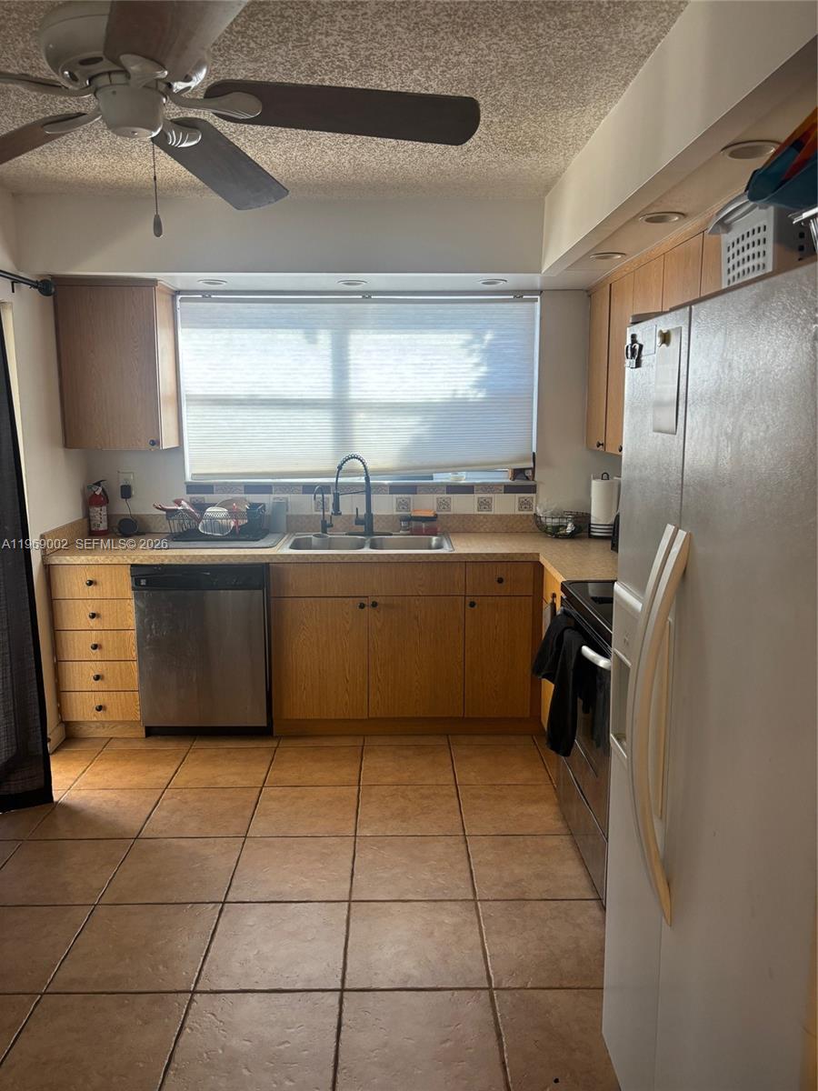 A kitchen features wood cabinets, stainless steel appliances, tile flooring, and a window above the sink — 2249 SE 27th Dr # D, Homestead FL 33035, HOMESTEAD, FL