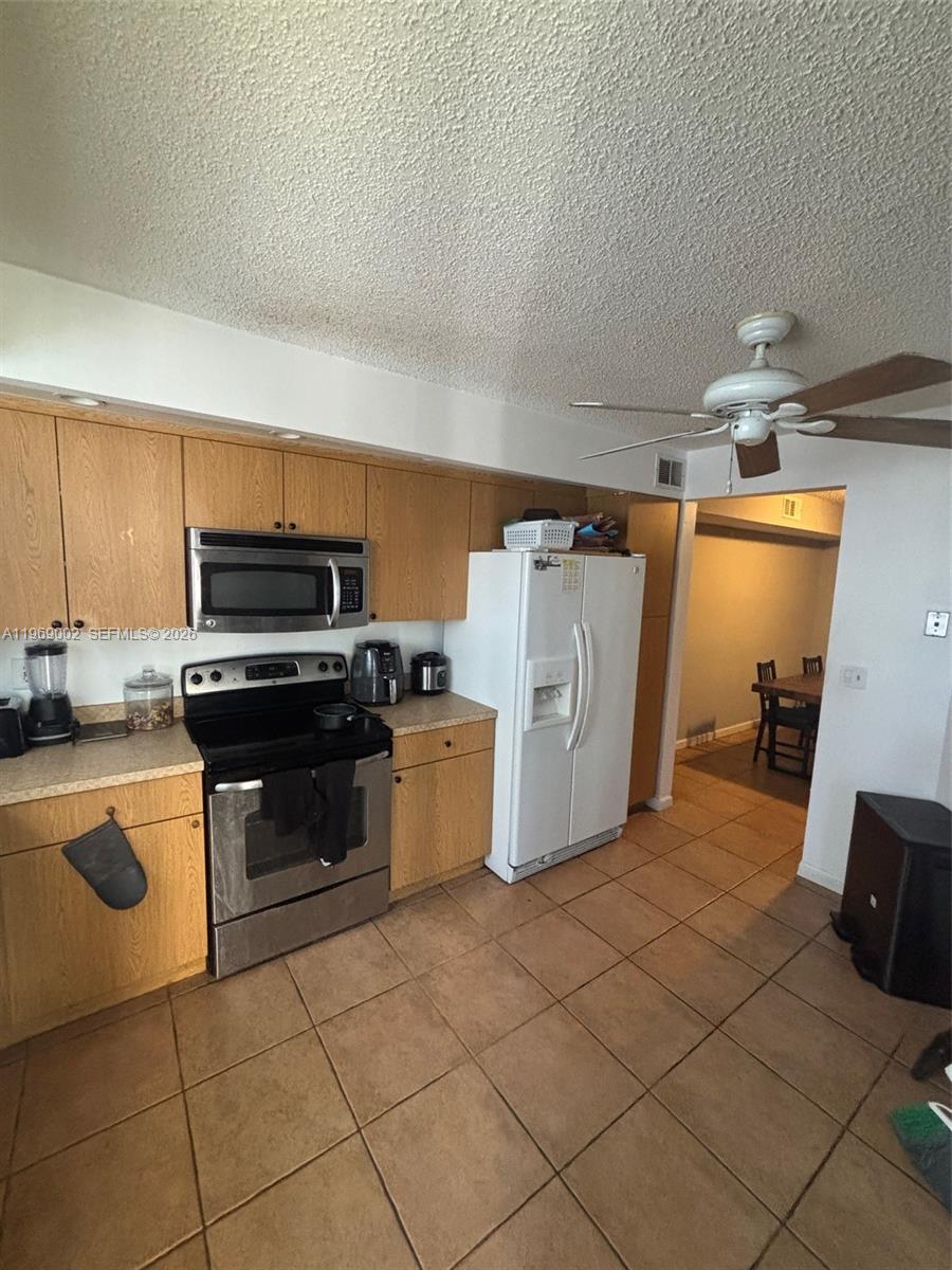 A kitchen features light wood cabinets, stainless steel appliances, a white refrigerator, and tiled flooring — 2249 SE 27th Dr # D, Homestead FL 33035, HOMESTEAD, FL