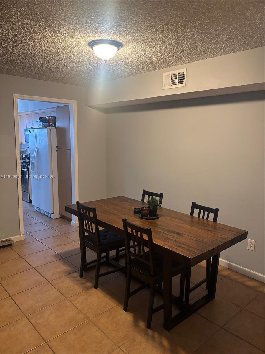 A dining area features a wooden table with four chairs on a tiled floor — 2249 SE 27th Dr # D, Homestead FL 33035, HOMESTEAD, FL