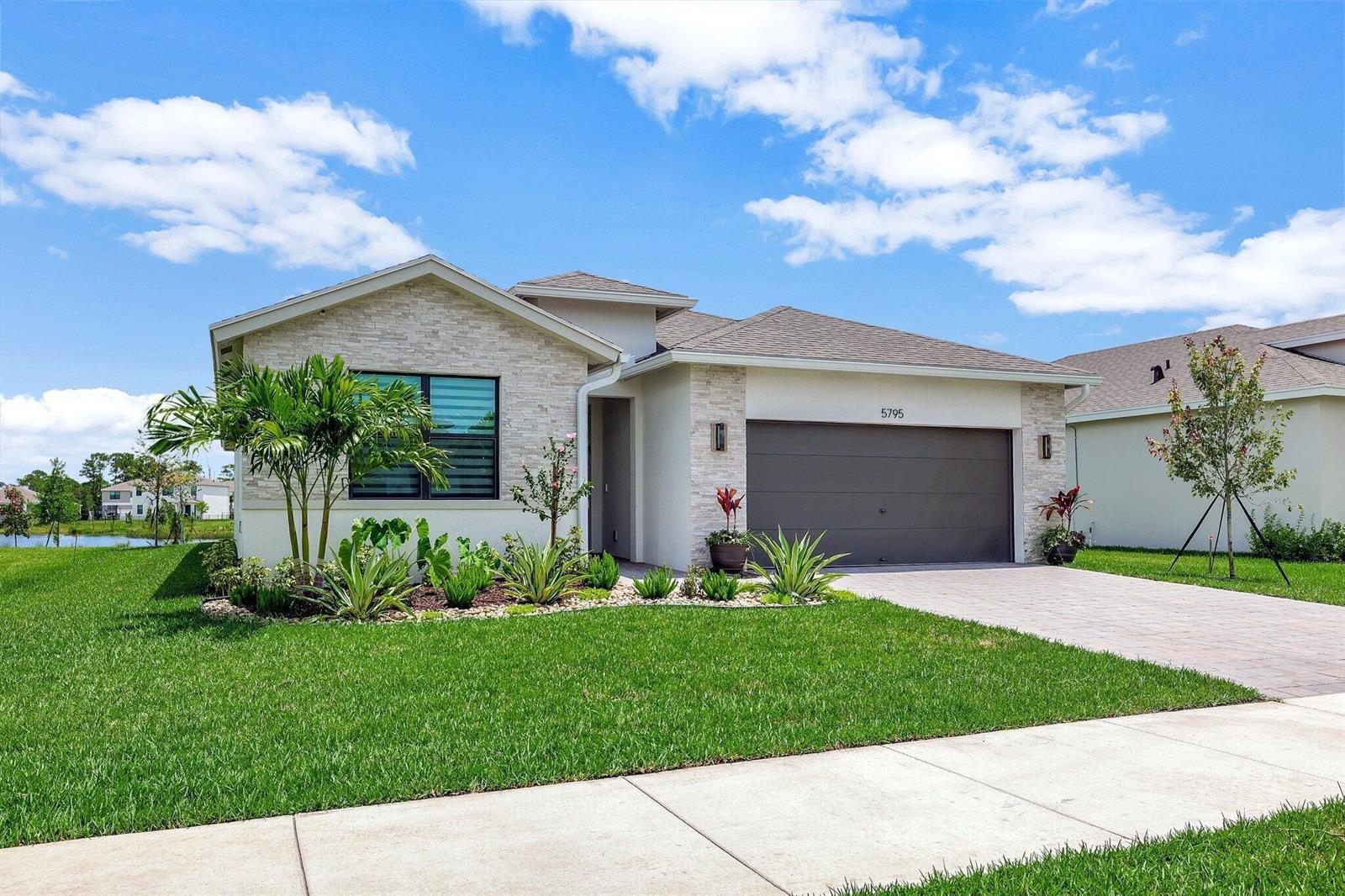 A single-story house features a stone facade, a two-car garage, and a landscaped front yard — 5795 SE Sky Blue Circle, Stuart FL 34997, STUART, FL