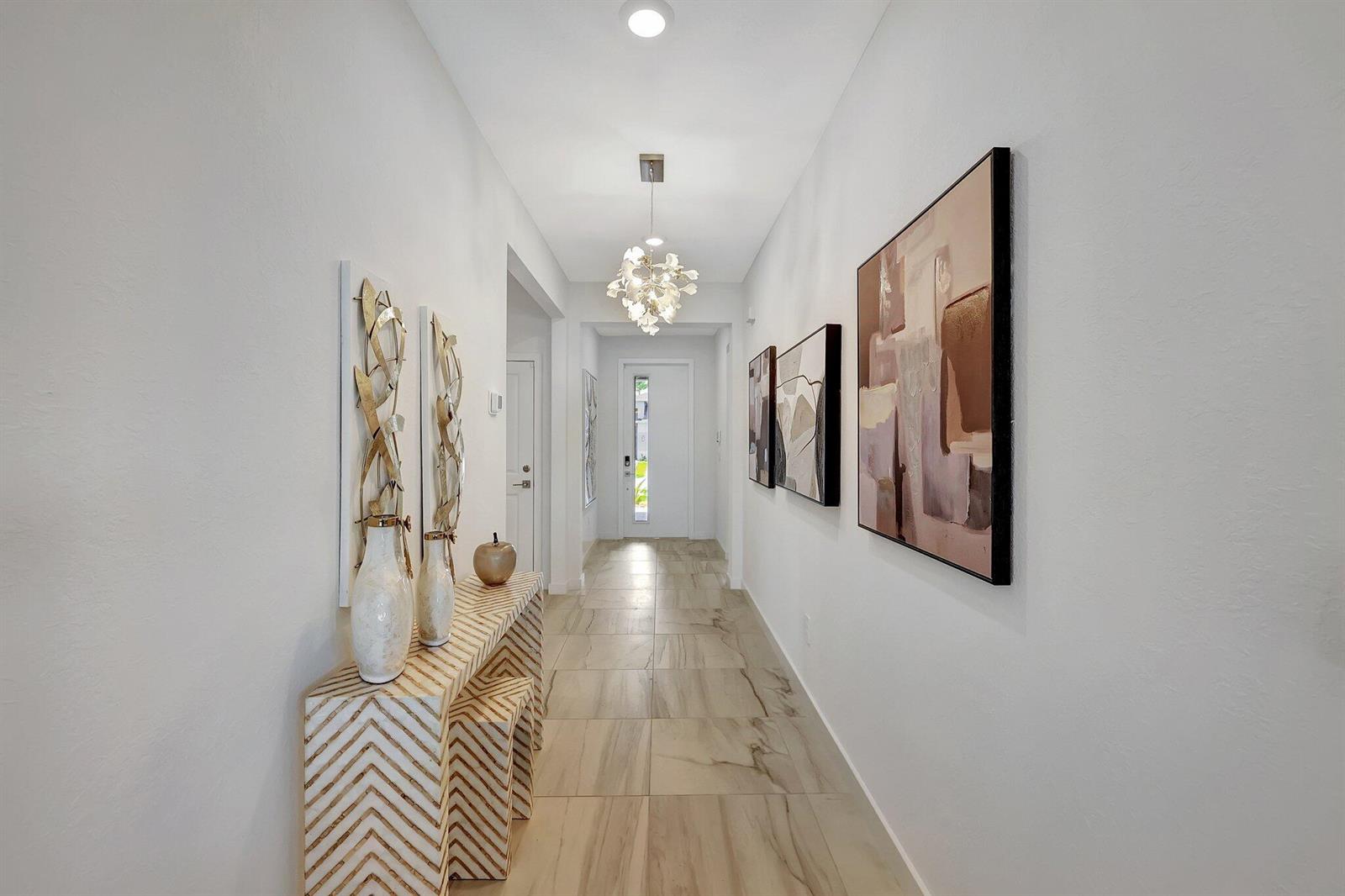 A bright hallway features light tile flooring, a decorative console table, and wall-mounted artwork — 5795 SE Sky Blue Circle, Stuart FL 34997, STUART, FL