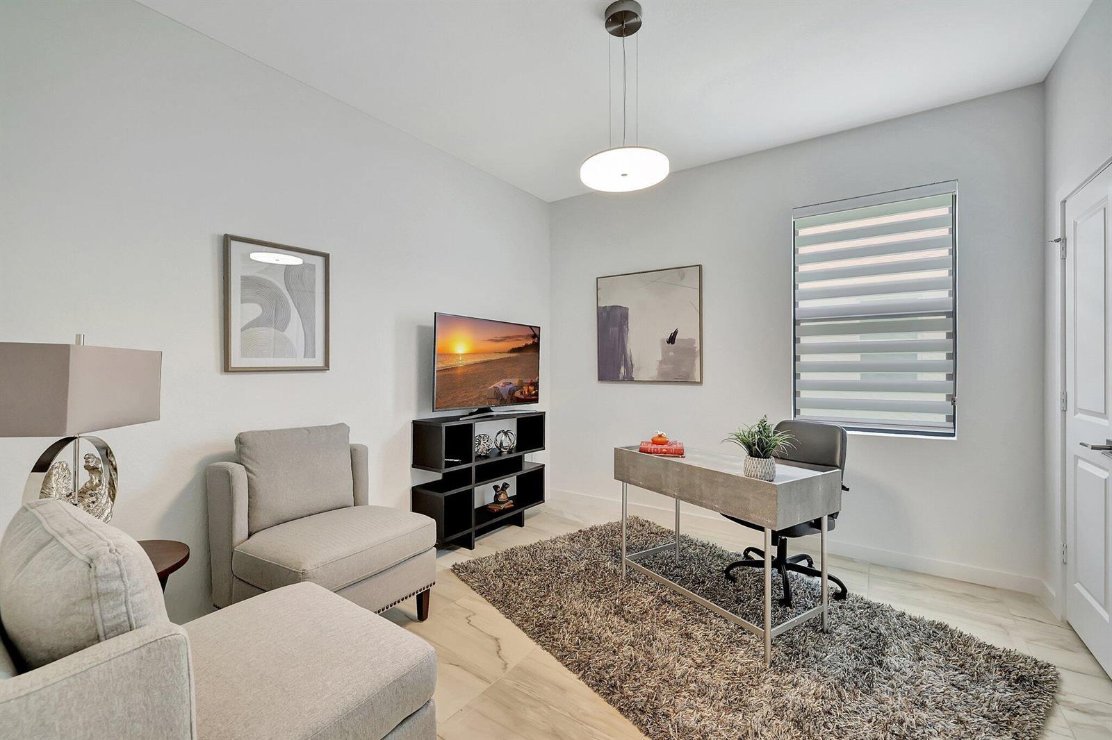 A home office features a desk, a television on a stand, and two gray armchairs — 5795 SE Sky Blue Circle, Stuart FL 34997, STUART, FL