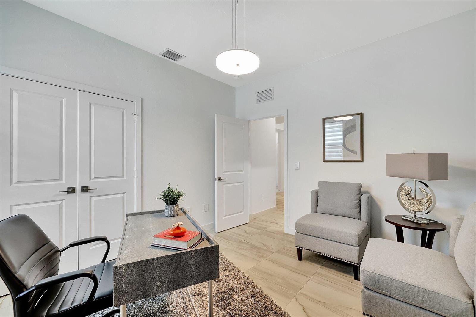 A home office features a desk, two gray armchairs, a side table, and tile flooring — 5795 SE Sky Blue Circle, Stuart FL 34997, STUART, FL