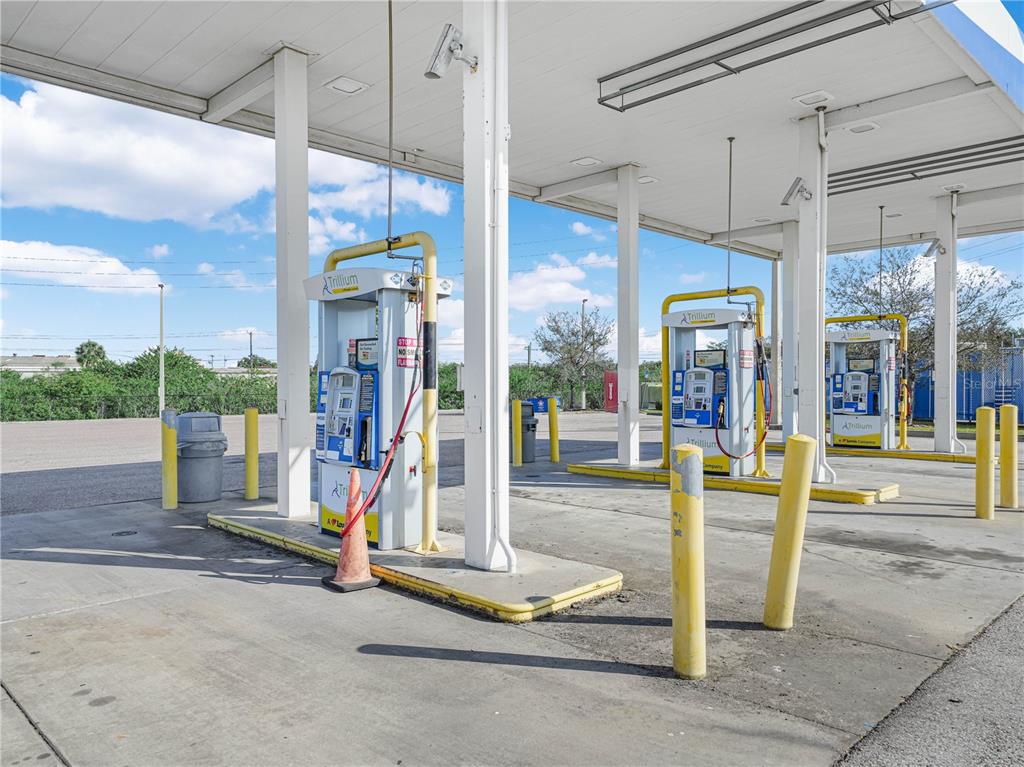 A commercial gas station canopy features three fuel pumps with yellow bollards on a concrete lot — 5030 MADISON AVENUE, TAMPA, FL