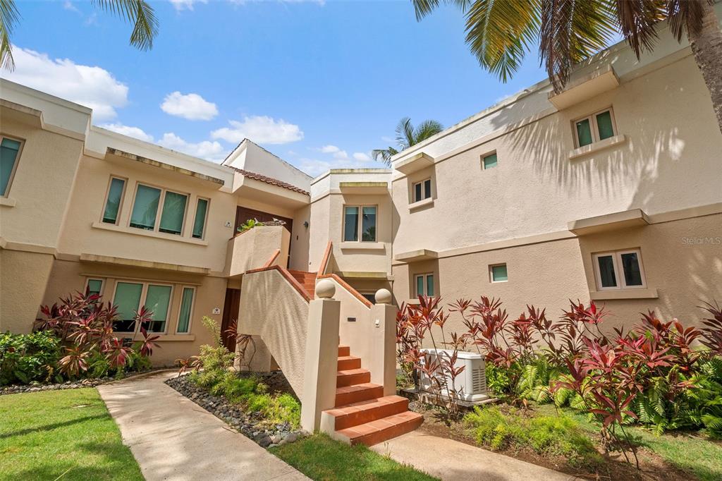 An exterior view of a two-story stucco building with a central staircase and landscaping — . LAKESIDE VILLAS UNIT D4, VEGA ALTA, PR