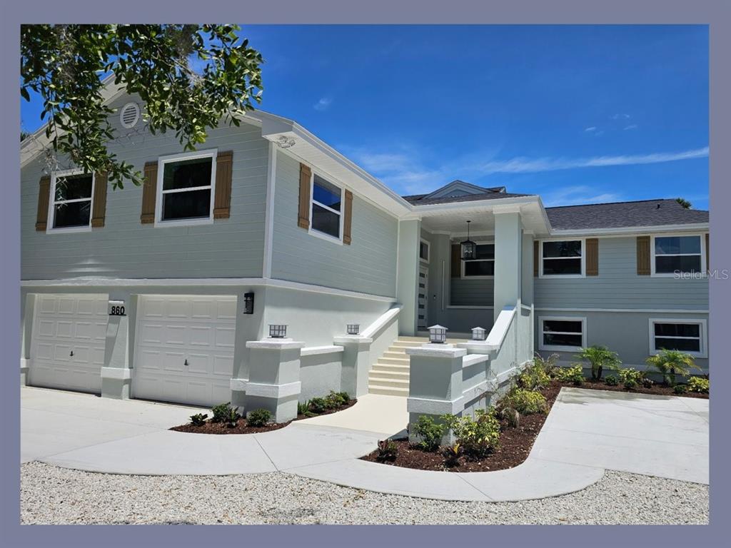 A two-story house with light green siding, a two-car garage, and a raised entryway — 860 LAMBERT AVENUE, FLAGLER BEACH, FL