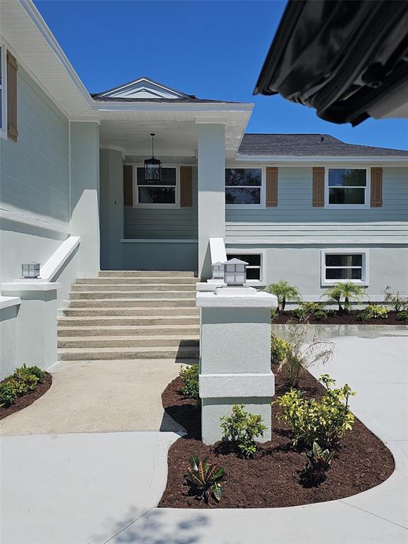 A light green house exterior features a concrete staircase leading to a covered entryway — 860 LAMBERT AVENUE, FLAGLER BEACH, FL