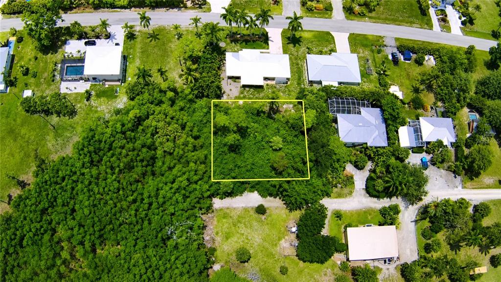 An aerial view shows a vacant, rectangular lot outlined in yellow surrounded by residential properties — 7455 GEORGIANA DRIVE, BOKEELIA, FL