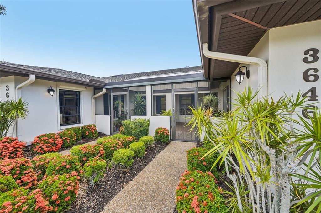 A walkway leads to the screened entryway of a house with white walls and landscaping — 3646 GLENEAGLE DRIVE UNIT 10B, SARASOTA, FL