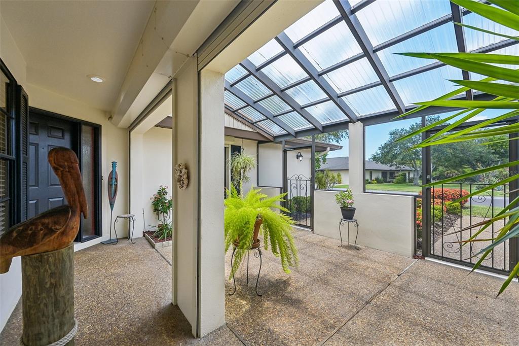 A covered patio with a translucent roof, concrete flooring, and a decorative wooden pelican statue — 3646 GLENEAGLE DRIVE UNIT 10B, SARASOTA, FL