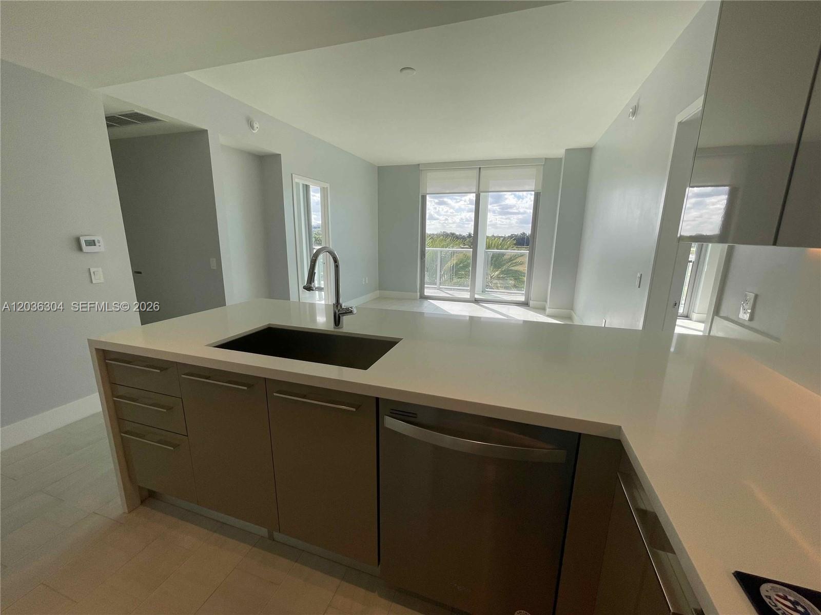 A modern kitchen features light-colored cabinetry, a white countertop, and a stainless steel dishwasher — 2000 Metropica Way # 307, Sunrise FL 33323, SUNRISE, FL