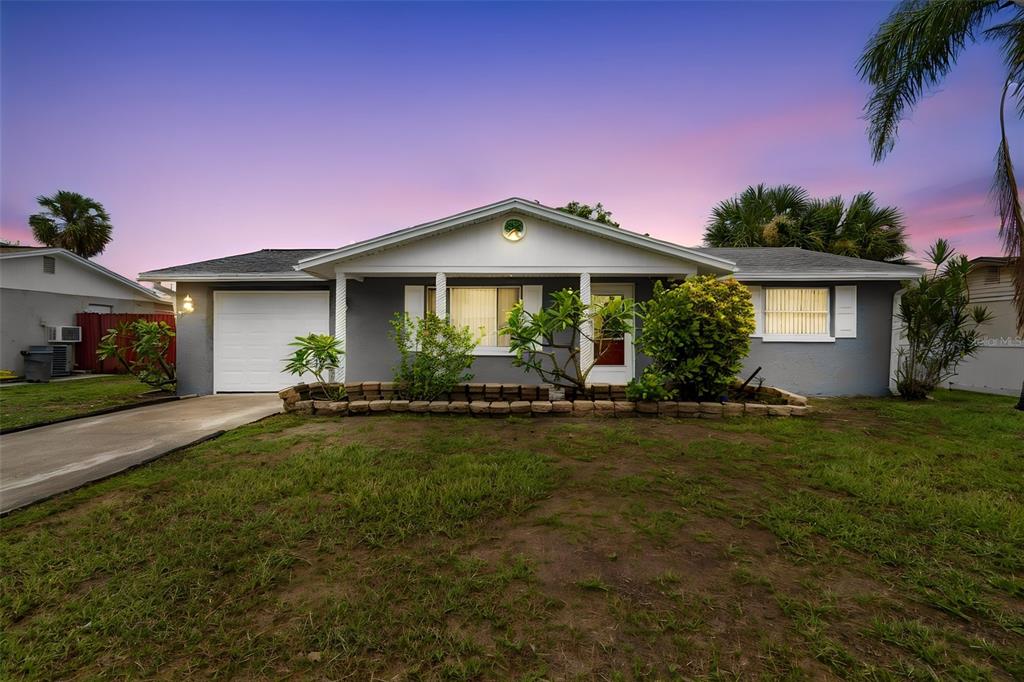 A single-story gray house with a white garage door and a stone garden bed — 3533 WILSON DRIVE, HOLIDAY, FL