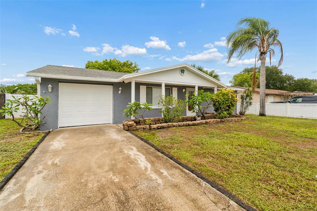 A single-story house with a gray exterior, a white garage door, and a concrete driveway — 3533 WILSON DRIVE, HOLIDAY, FL