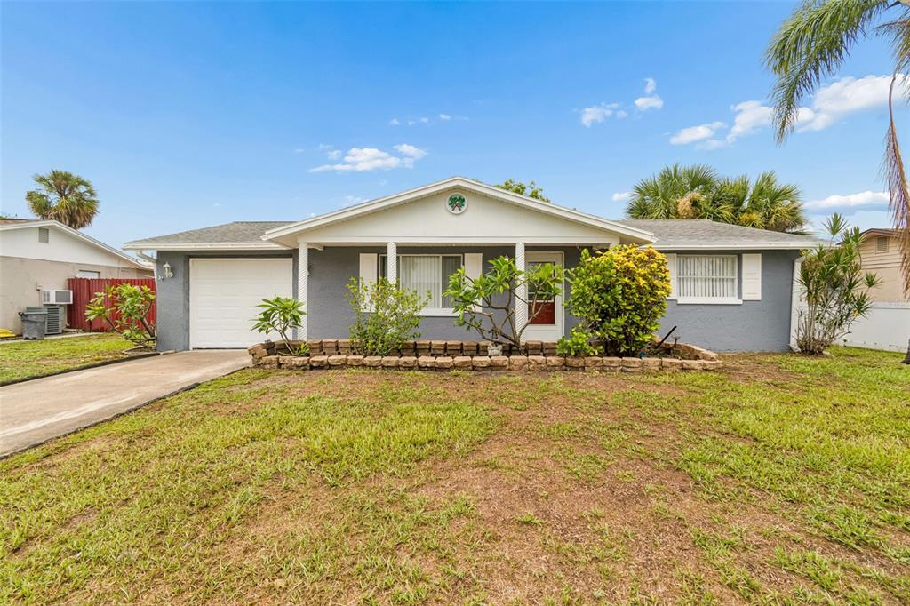 A single-story gray house with a white garage door and a front garden bed — 3533 WILSON DRIVE, HOLIDAY, FL
