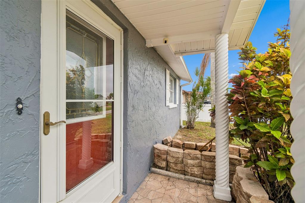 A covered porch features a white storm door, a spiral column, and a stone planter — 3533 WILSON DRIVE, HOLIDAY, FL