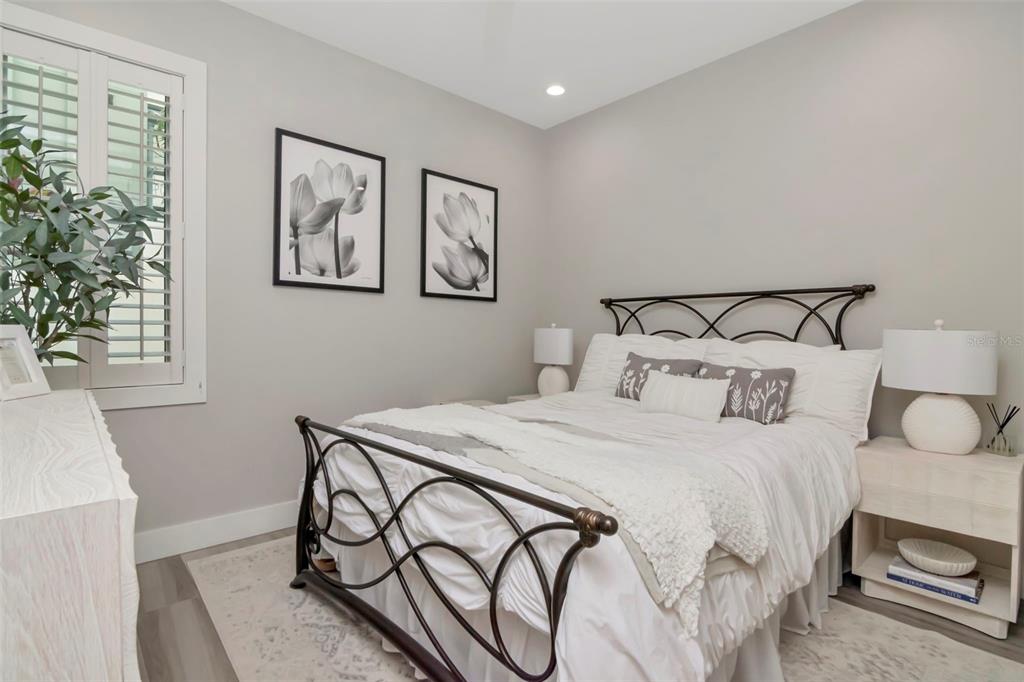A bedroom features a light-colored upholstered bed, a ceiling fan, and an attached bathroom — 536 4TH AVENUE S UNIT 2, ST PETERSBURG, FL