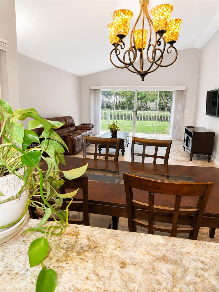 A dining area with a glass-topped table leads to a living room with sliding doors — 10750 NW 10th St, Plantation FL 33322, PLANTATION, FL
