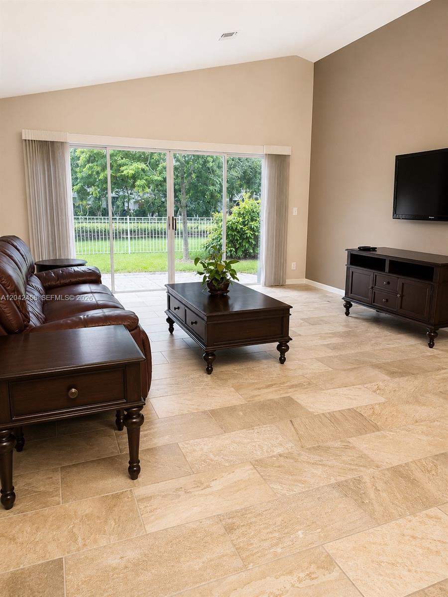 A living room features tile floors, a brown leather sofa, and sliding glass doors — 10750 NW 10th St, Plantation FL 33322, PLANTATION, FL
