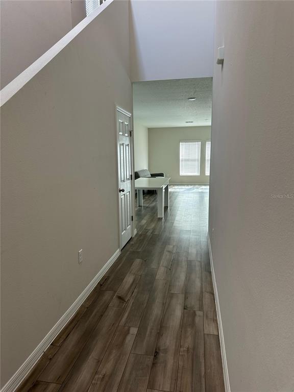 A hallway with wood-look tile flooring leads to a living area with a white table — 1572 ELLESMERE AVENUE, HAINES CITY, FL