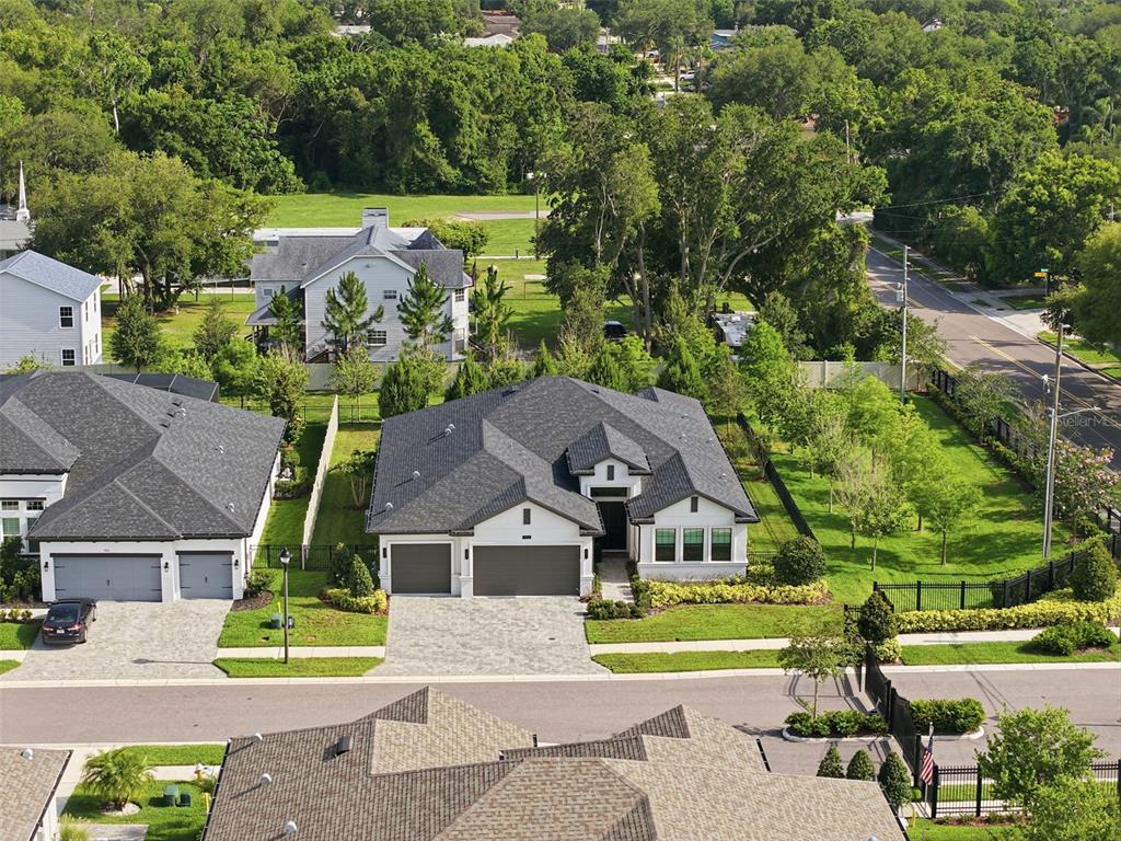 An aerial view shows a modern single-story house with a gray roof and paver driveway — 1916 JULLEE LANE, PALM HARBOR, FL