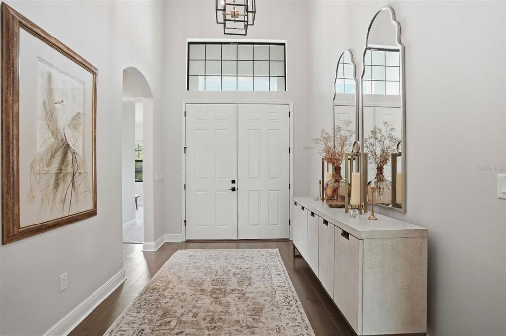 A bright entryway features a double door, a long console table, and two arched mirrors — 1916 JULLEE LANE, PALM HARBOR, FL