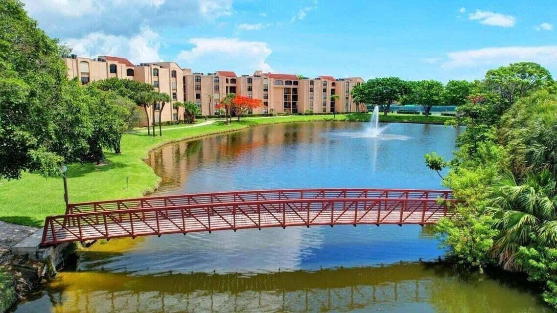 A red pedestrian bridge spans a pond with a fountain in front of apartment buildings — 2255 Lindell Boulevard # 4103, Delray Beach FL 33444, DELRAY BEACH, FL