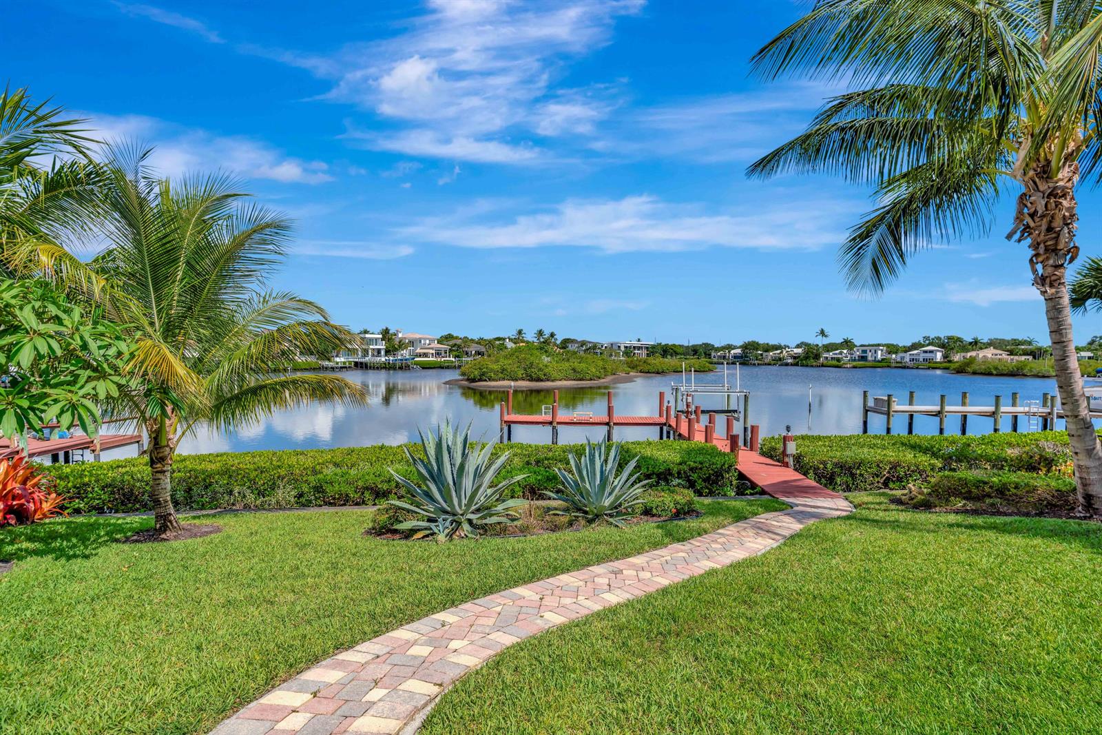 A paved walkway leads through a grassy lawn to a wooden dock on a canal — 102 Victory Drive, Jupiter FL 33477, JUPITER, FL