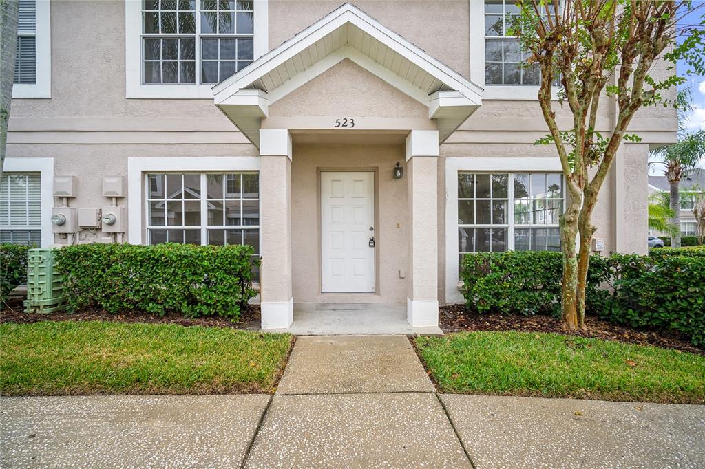 The exterior of a beige two-story building features a covered entryway with a white door — 523 KENSINGTON LAKE N, BRANDON, FL