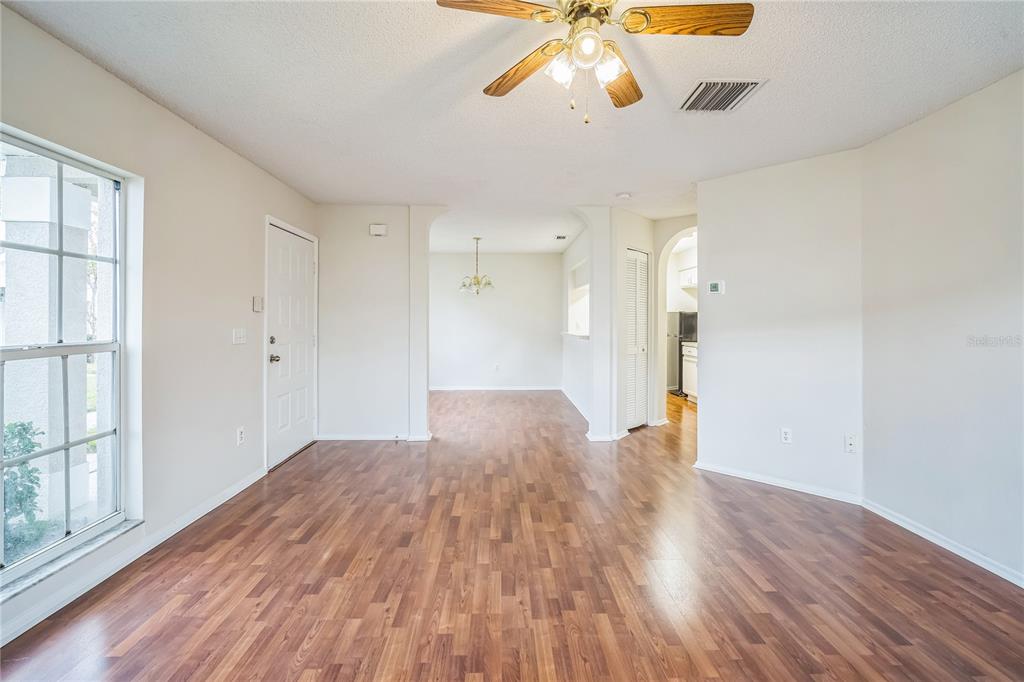 An empty room with wood-look flooring, a ceiling fan, and an arched entryway — 523 KENSINGTON LAKE N, BRANDON, FL