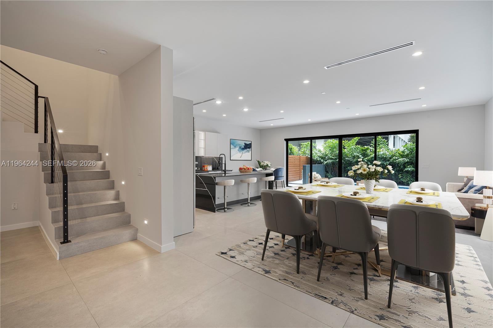 A modern open-concept dining area and kitchen feature gray tile floors and a staircase — 2962 W Trade Ave, Coconut Grove FL 33133, COCONUT GROVE, FL