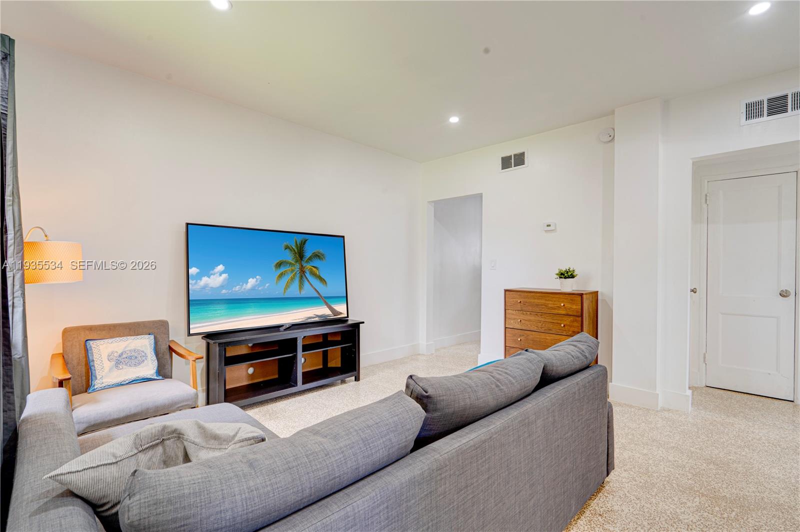 A living room features a grey sofa, a television on a stand, and a wooden dresser — 234 NE 111th St # 1, Miami FL 33161, MIAMI, FL