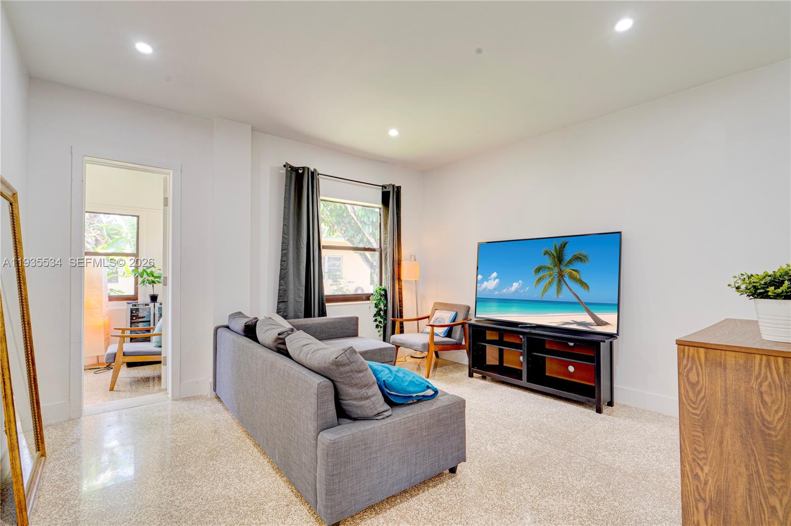 A living room features a grey sofa, a television on a stand, and tiled floors — 234 NE 111th St # 1, Miami FL 33161, MIAMI, FL
