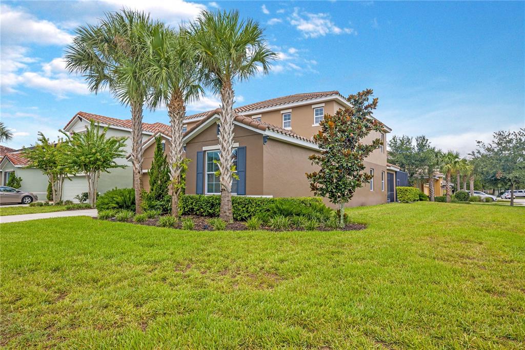 A two-story suburban house with a tan exterior, blue shutters, and palm trees in front — 5207 WILDWOOD WAY, DAVENPORT, FL