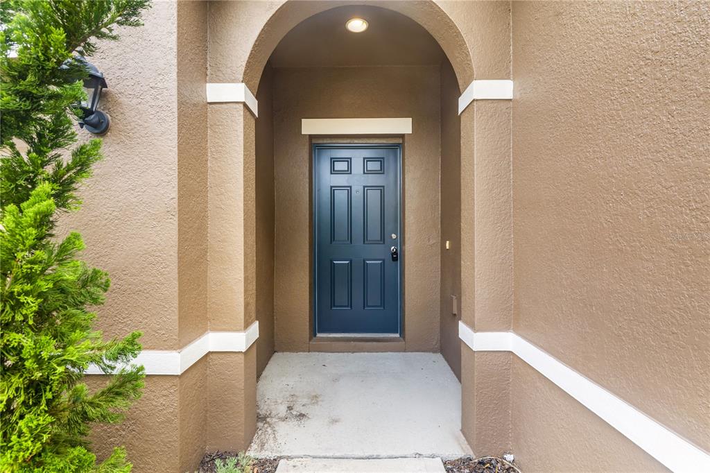 A blue front door is set within a tan stucco arched entryway — 5207 WILDWOOD WAY, DAVENPORT, FL