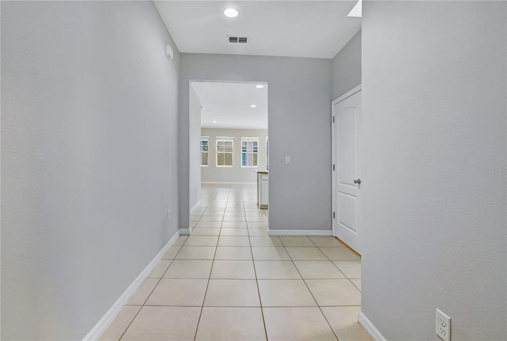 A tiled hallway leads toward an open kitchen area with light gray walls — 5207 WILDWOOD WAY, DAVENPORT, FL