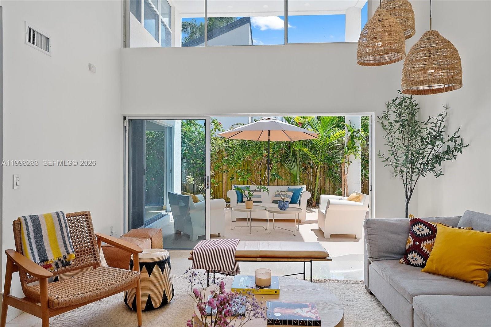 A bright living room opens through sliding glass doors to a patio with outdoor seating — 2721 SW 22nd Ave # A, Miami FL 33133, MIAMI, FL