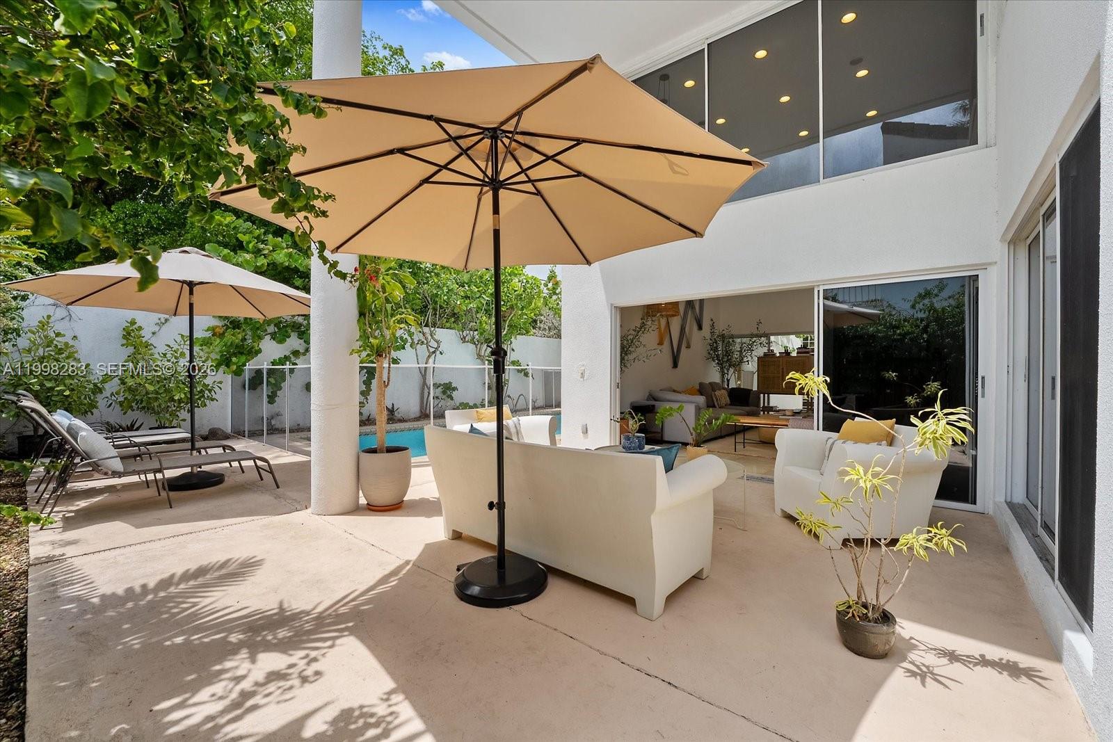A patio features a seating area with white furniture, umbrellas, and a swimming pool — 2721 SW 22nd Ave # A, Miami FL 33133, MIAMI, FL