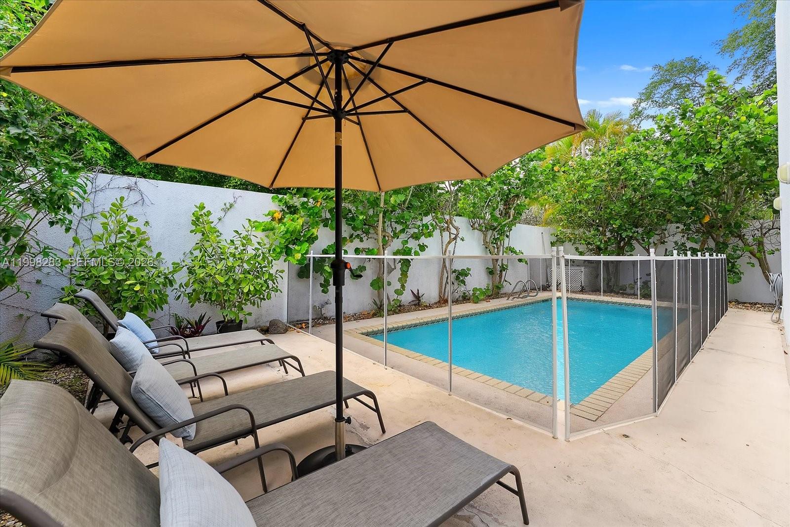 A swimming pool with a safety fence is surrounded by lounge chairs and an umbrella — 2721 SW 22nd Ave # A, Miami FL 33133, MIAMI, FL