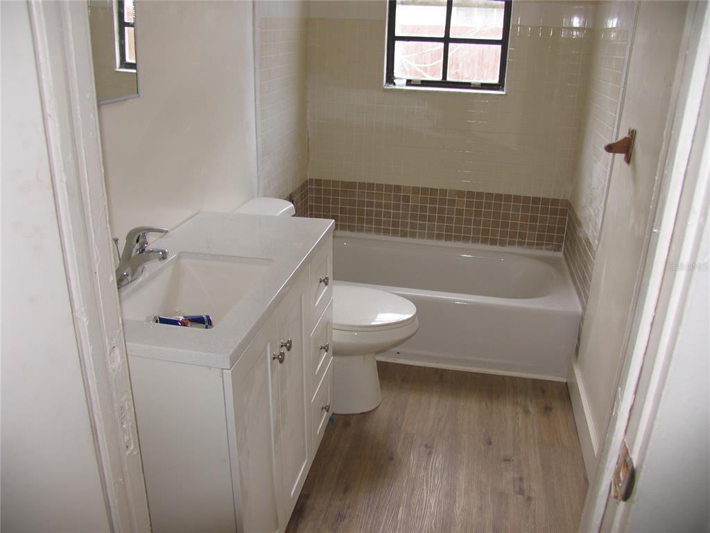 A bathroom features a white vanity, a toilet, and a bathtub with tiled walls — 323 DOVER STREET, ORLANDO, FL