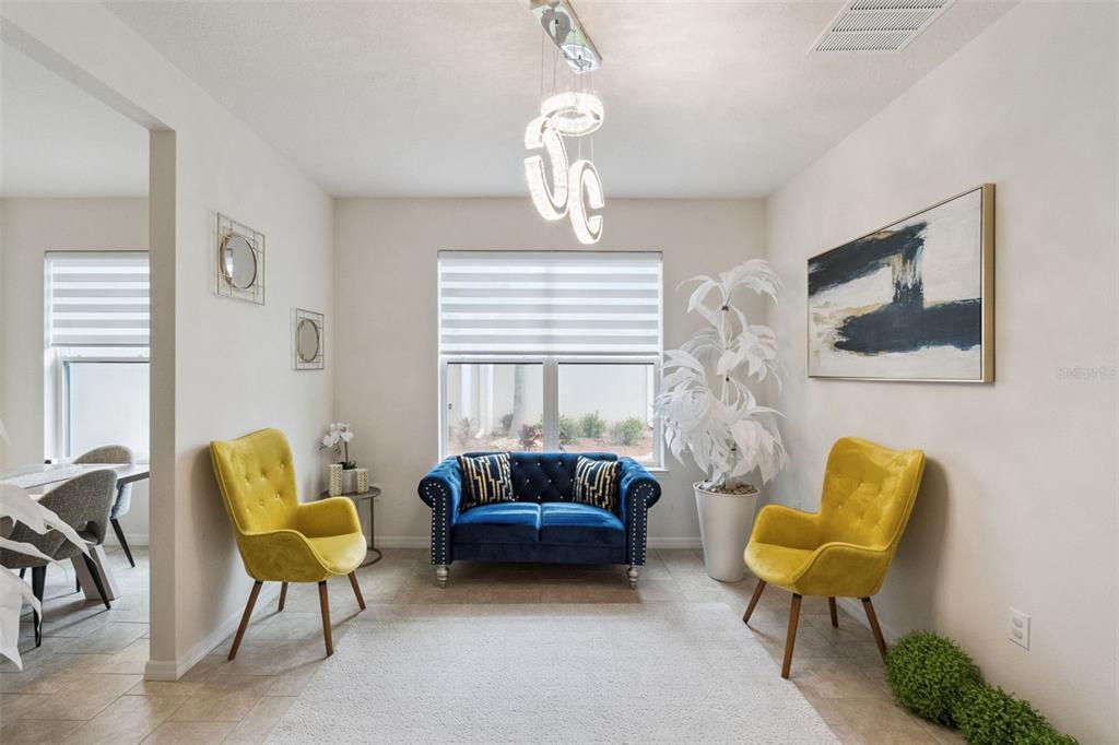 A sitting room features two yellow armchairs, a blue loveseat, and a modern chandelier — 3849 CARRICK BEND DRIVE, KISSIMMEE, FL