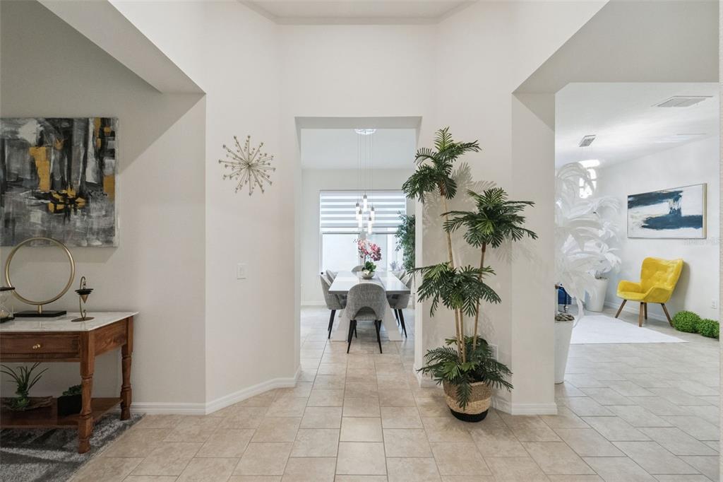 A bright foyer leads to a dining area with a table, chairs, and a potted plant — 3849 CARRICK BEND DRIVE, KISSIMMEE, FL