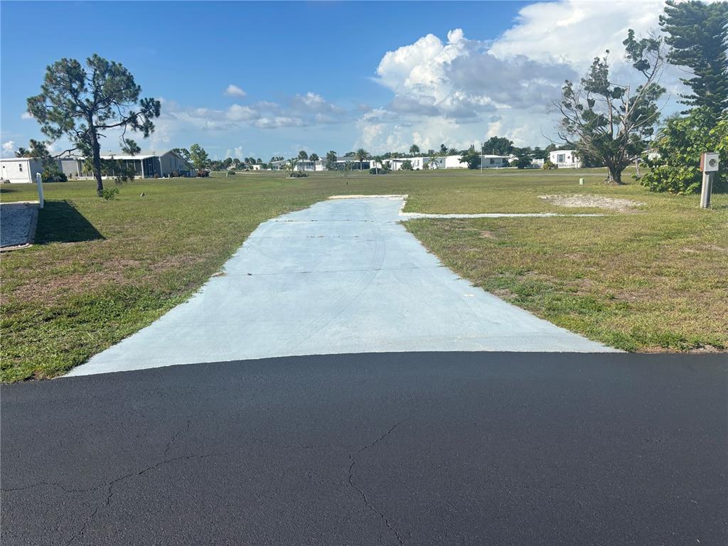 A paved driveway leads to a vacant grassy lot in a residential neighborhood — 7381 CANDACE LANE, PORT CHARLOTTE, FL